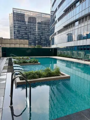 a swimming pool in front of a building with tall buildings at Luxury-Styled 2BR Uptown T2 Parksuites BGC in Manila
