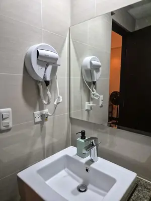 a bathroom with a sink and a hair dryer on the wall at Jacob's Place Near Manila Airport in Manila