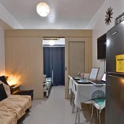 a living room with a couch and a table and a refrigerator at MOA Staycation - Sea Residences - Tower C in Manila