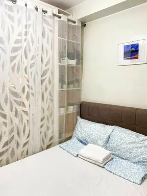 a bedroom with a bed with a curtain and a bed sidx sidx at Shore Residences Condo MOA NAIA with Netflix WiFi Access in Manila