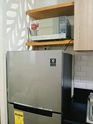 a microwave sitting on top of a refrigerator in a kitchen at Shore Residences Condo MOA NAIA with Netflix WiFi Access in Manila