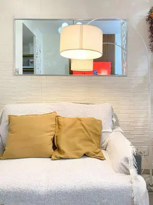 a bed with a yellow pillow and a mirror at Shore Residences Condo MOA NAIA with Netflix WiFi Access in Manila
