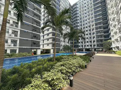 a walkway with palm trees in a city with buildings at Shore Residences Condo MOA NAIA with Netflix WiFi Access in Manila