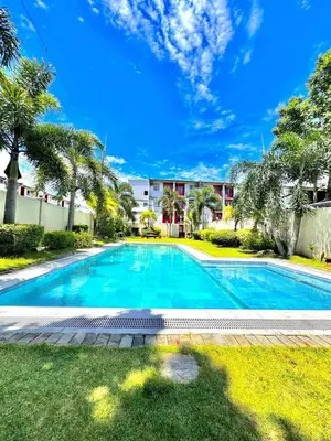 a swimming pool in a yard with palm trees at Jade Condo Netflix Wifi Karaoke with Cinema Projector in Imus