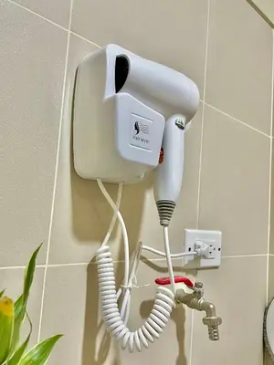 a white hair dryer is hanging on a wall at Kabina Suites at Fame Residences in Manila