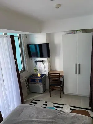 a bedroom with a bed and a tv on the wall at AFFORDABLE STAYCATION NEAR Airport in Manila