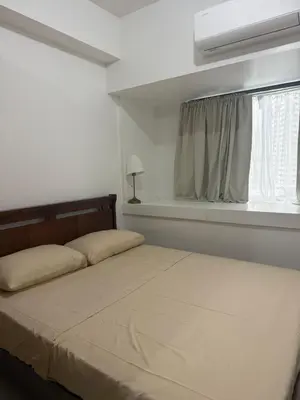 a bedroom with a bed and a window with a curtain at The Fortress at SMDC The Lush Residences in Manila