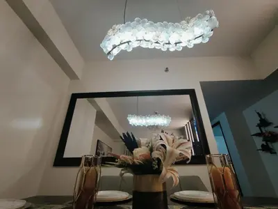 a dining room table with a mirror and a chandelier at Jpad Suites in Manila