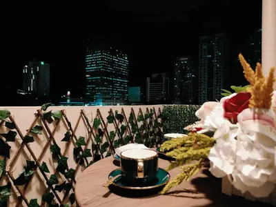 a table with a candle and flowers on a balcony at Jpad Suites in Manila