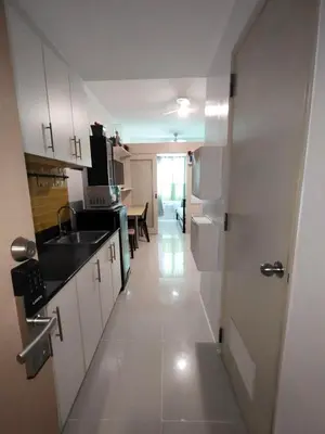 a kitchen with white cabinets and a sink and a table at Lornas Staycation in Manila