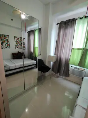a room with a mirror and a bed and a chair at Lornas Staycation in Manila
