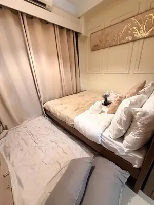 two beds in a small room with avertisement for at Relaxing 1BR Condo near MOA & NAIA with WiFi, PS4, Karaoke in Manila