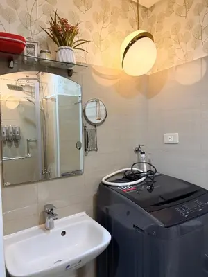 a bathroom with a sink and a trash can and a mirror at Relaxing 1BR Condo near MOA & NAIA with WiFi, PS4, Karaoke in Manila