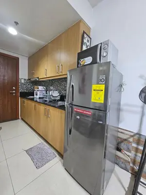a stainless steel refrigerator in a kitchen with wooden cabinets at Shore Residences Tower D Viann in Manila