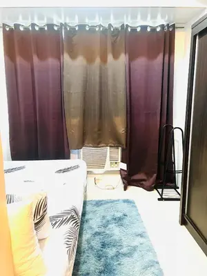 a room with curtains and a bed and a rug at Sea Residences Elegant Place by Bella in Manila
