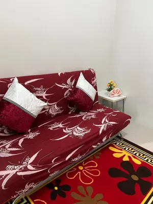a bed with red sheets and pillows on a rug at Sea Residences Elegant Place by Bella in Manila