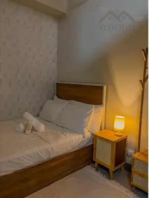 a bedroom with a bed and a night stand with a lamp at Wooden White in Manila