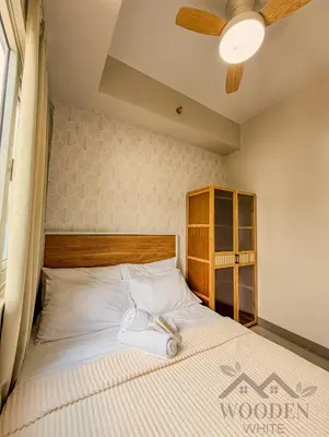 a bed with a wooden headboard in a bedroom at Wooden White in Manila