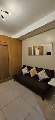a living room with a black couch with pillows at The Executive Suites by PJTai Realty Shell002 - 1BR in Manila