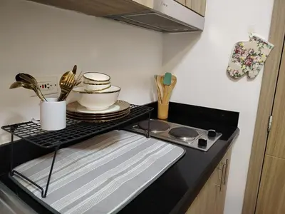 a kitchen counter with a tray with plates and utensils at PROMO Modern Boho Chic Condo Near MOA, Manila Bay in Manila