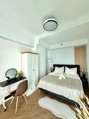a bedroom with a bed and a desk and a bed and a chair at The Global Nest at Anuva Modern 1BR with Pool in Manila