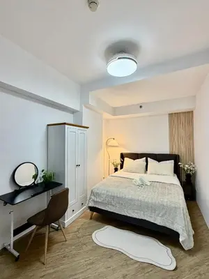 a bedroom with a bed and a desk and a bed sidx sidx sidx at The Global Nest at Anuva Modern 1BR with Pool in Manila