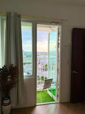 a sliding glass door with a chair on a balcony at The Global Nest at Anuva Modern 1BR with Pool in Manila