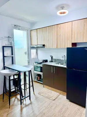 a kitchen with a table and a sink and a refrigerator at The Global Nest at Anuva Modern 1BR with Pool in Manila