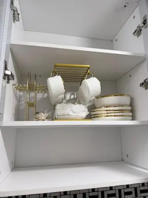 a white cabinet filled with plates and dishes at 2 BR Modern Apartment Near the Airport in Manila