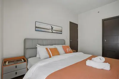 a bedroom with a large bed with orange and white pillows at Sunset Retreat - 4 Bedroom Home near Solaire 14pax in Manila