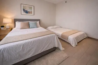 a bedroom with two beds and a lamp and a rug at Sunset Retreat - 4 Bedroom Home near Solaire 14pax in Manila