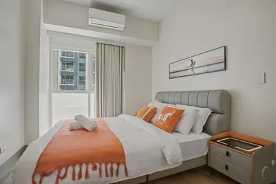 a bedroom with a bed with orange pillows and a window at Sunset Retreat - 4 Bedroom Home near Solaire 14pax in Manila