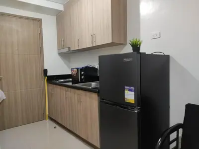 a kitchen with a black refrigerator and wooden cabinets at Shore 2 Residences Tower 1 JayDa in Manila