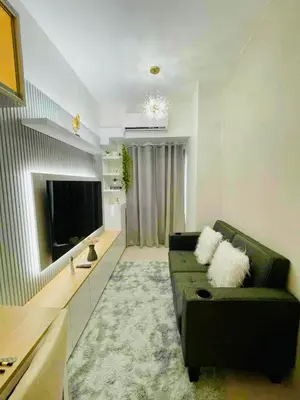 a living room with a couch and a flat screen tv at JL's City Hideaway at Fame Residences in Manila