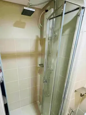 a shower with a glass door in a bathroom at JL's City Hideaway at Fame Residences in Manila