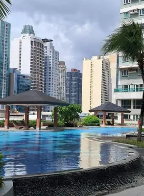 a large swimming pool with umbrellas in a city at Next Abode 1BR at TheBeaconMakati in Manila