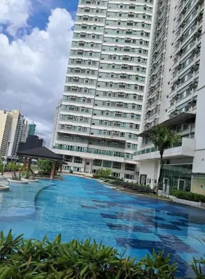 a large building with a large swimming pool in front of it at Next Abode 1BR at TheBeaconMakati in Manila