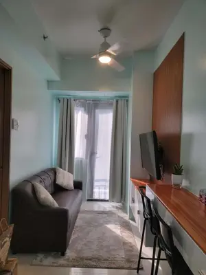 a living room with a couch and a television at The Nook at the Shore in Manila
