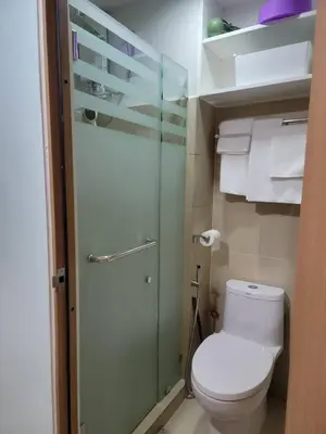 a small bathroom with a toilet and a shower at The Nook at the Shore in Manila
