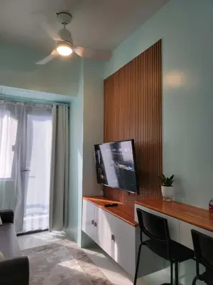 a living room with a television and a desk with chairs at The Nook at the Shore in Manila