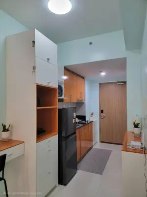 a kitchen with white cabinets and a black refrigerator at The Nook at the Shore in Manila