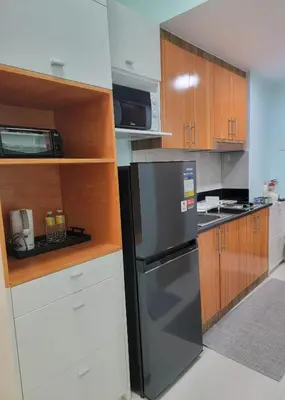 a kitchen with a stainless steel refrigerator and wooden cabinets at The Nook at the Shore in Manila