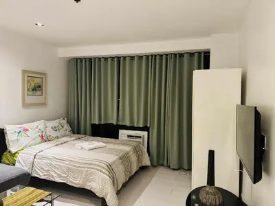 a bedroom with a bed and a television in it at The Gramercy Residences in Manila