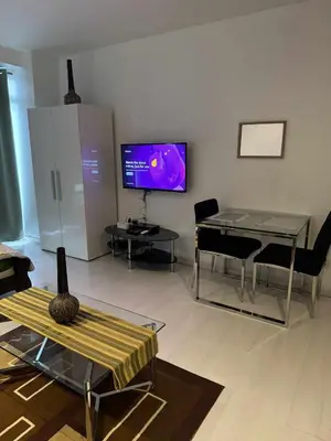 a living room with a table and a tv on the wall at The Gramercy Residences in Manila