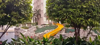 a yellow slide in a park with trees and water at DIRECT TO POOL Shore Residences by heart in Manila
