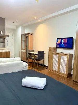 a hotel room with two beds and a table and a flat screen tv at The Gramercy Residences in Manila