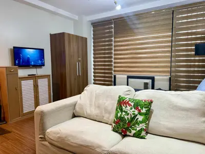 a living room with a couch and a television at The Gramercy Residences in Manila