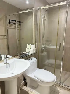 a bathroom with a toilet and a sink and a shower at The Gramercy Residences in Manila
