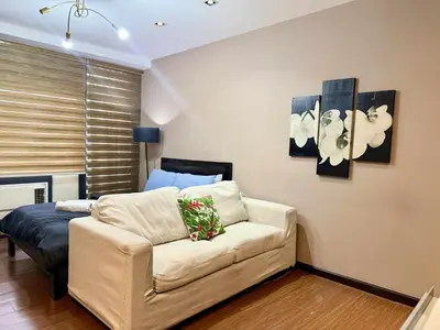 a living room with a couch and paintings on the wall at The Gramercy Residences in Manila
