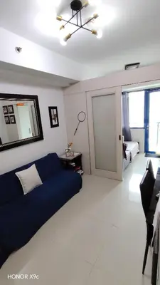 a living room with a blue couch and a bedroom at She'll residences condotel in Manila